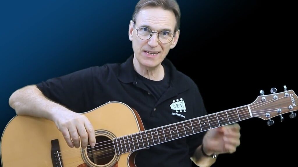 John Chamley playing acoustic guitar in the beginner course trailer